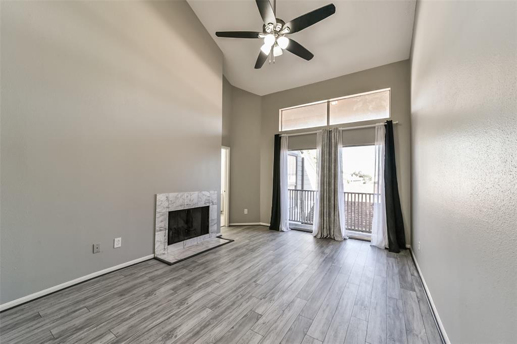 an empty room with wooden floor fireplace and windows