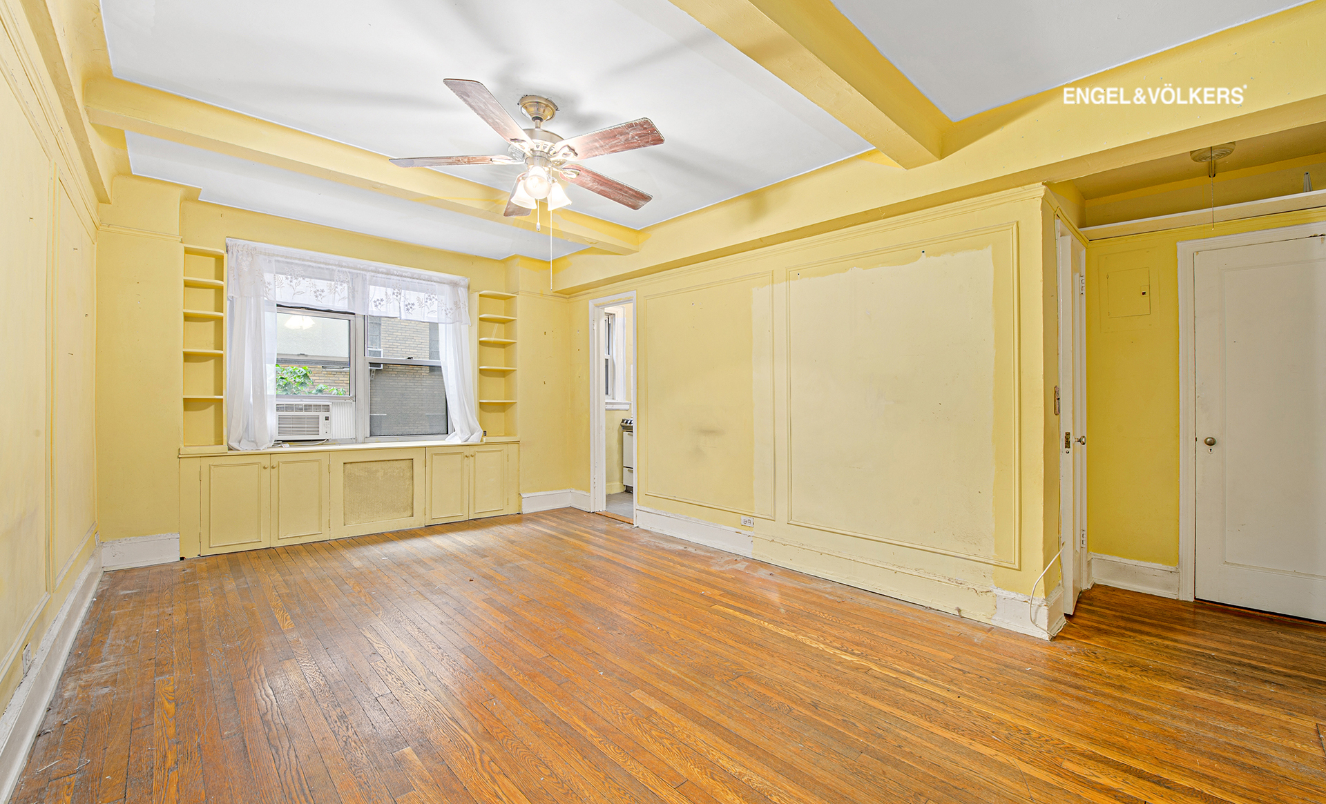 a view of an empty room with wooden floor and a window