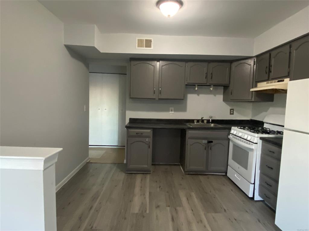 a kitchen with a sink and wooden floor