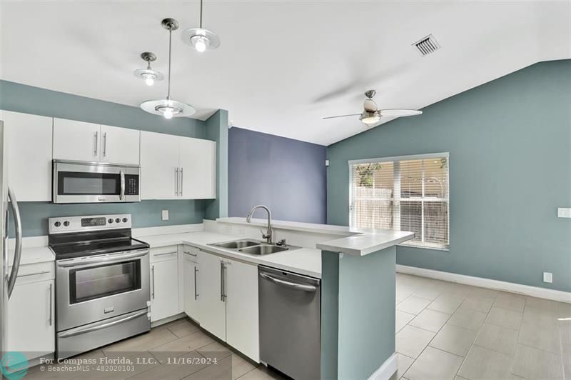 a kitchen with stainless steel appliances kitchen island a stove a sink and a microwave