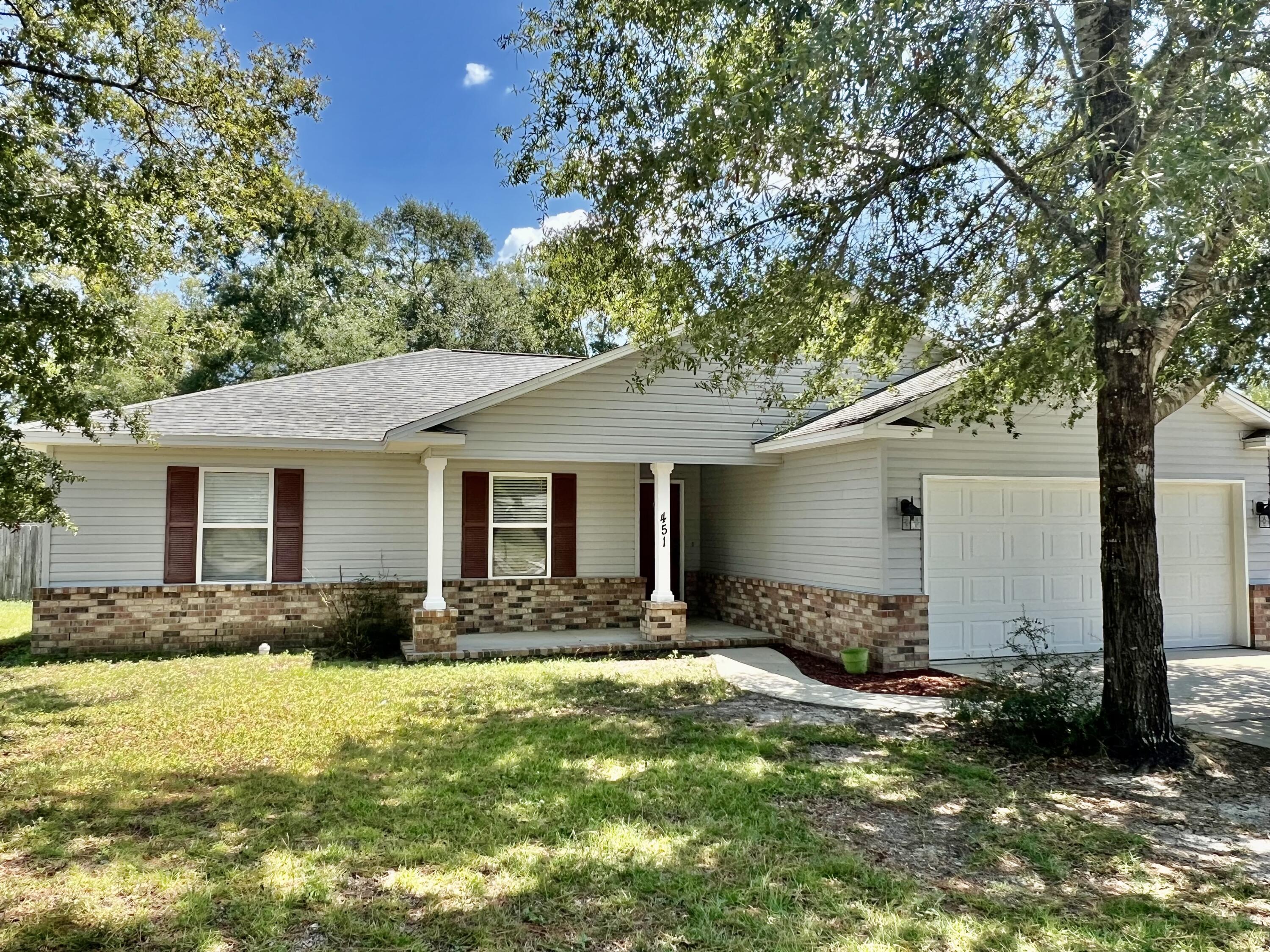 a front view of house with yard and trees around