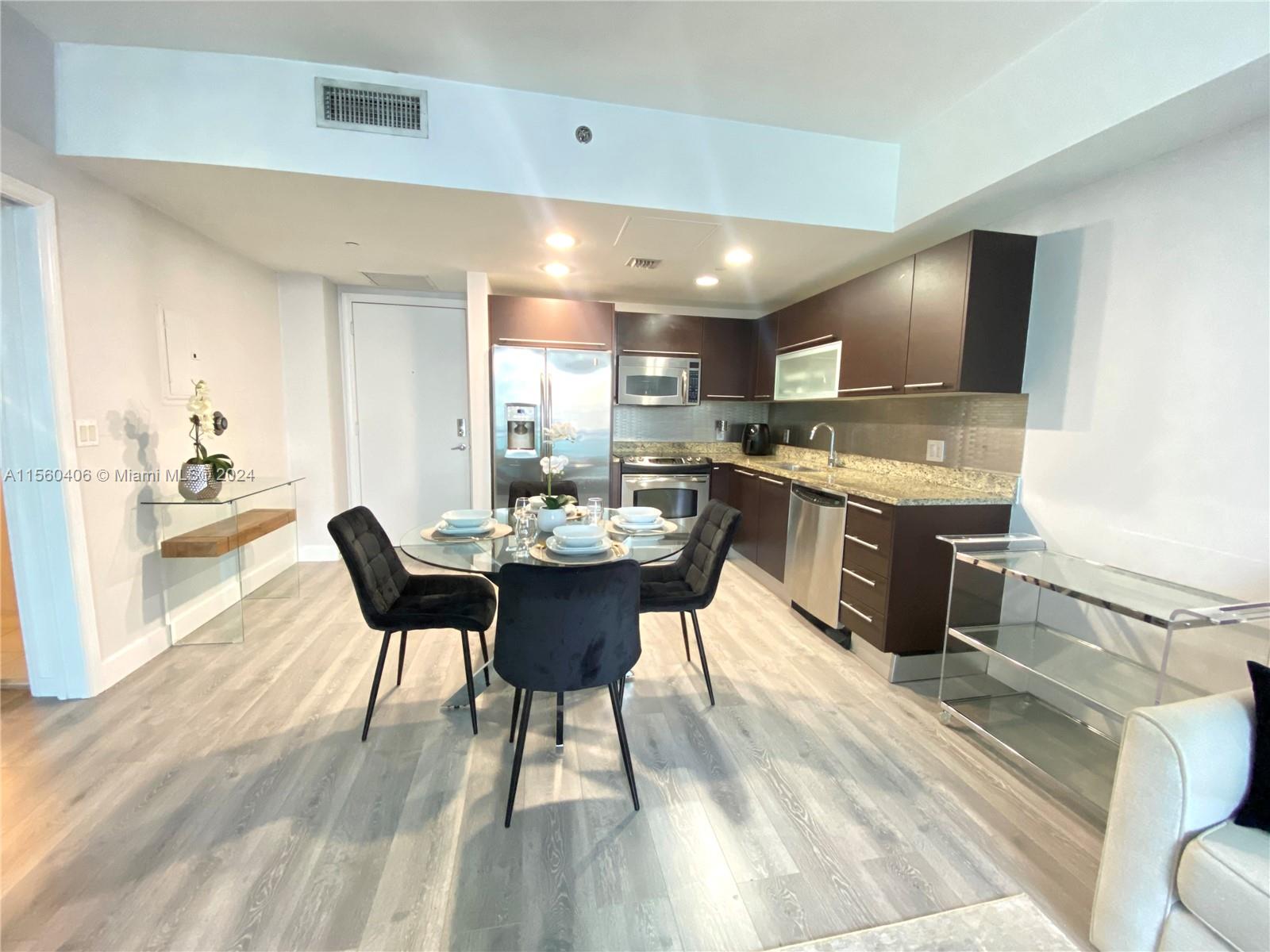 a kitchen with a dining table chairs and refrigerator