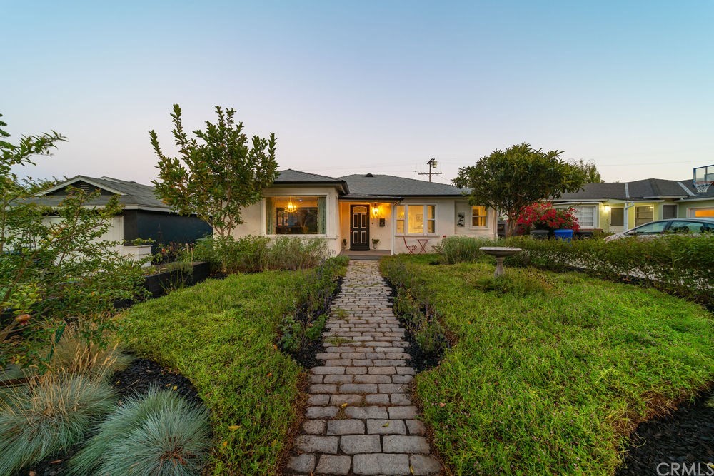 a front view of a house with a yard and potted plants