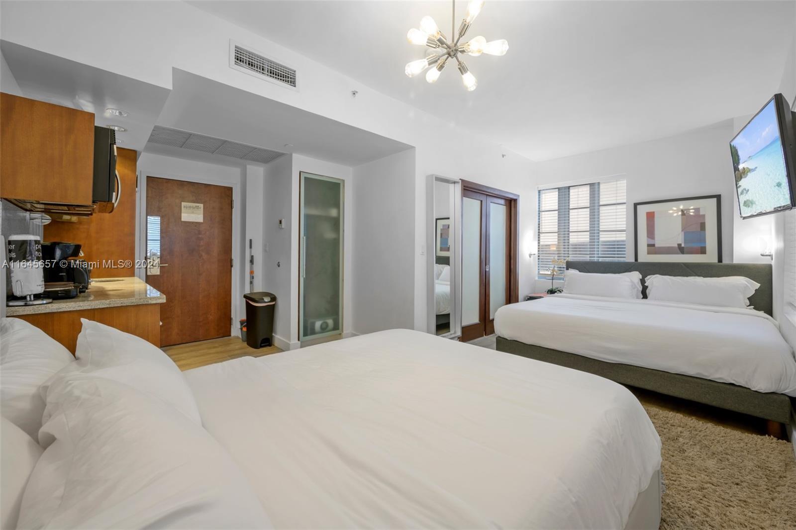 a spacious bedroom with a large bed and a chandelier