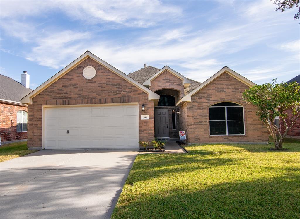 This is a single-story brick home featuring a two-car garage, arched entryway, and a large front window. The property has a well-maintained lawn and a welcoming aesthetic. Katy Area near shopping, minutes from I10, 99 and 290.