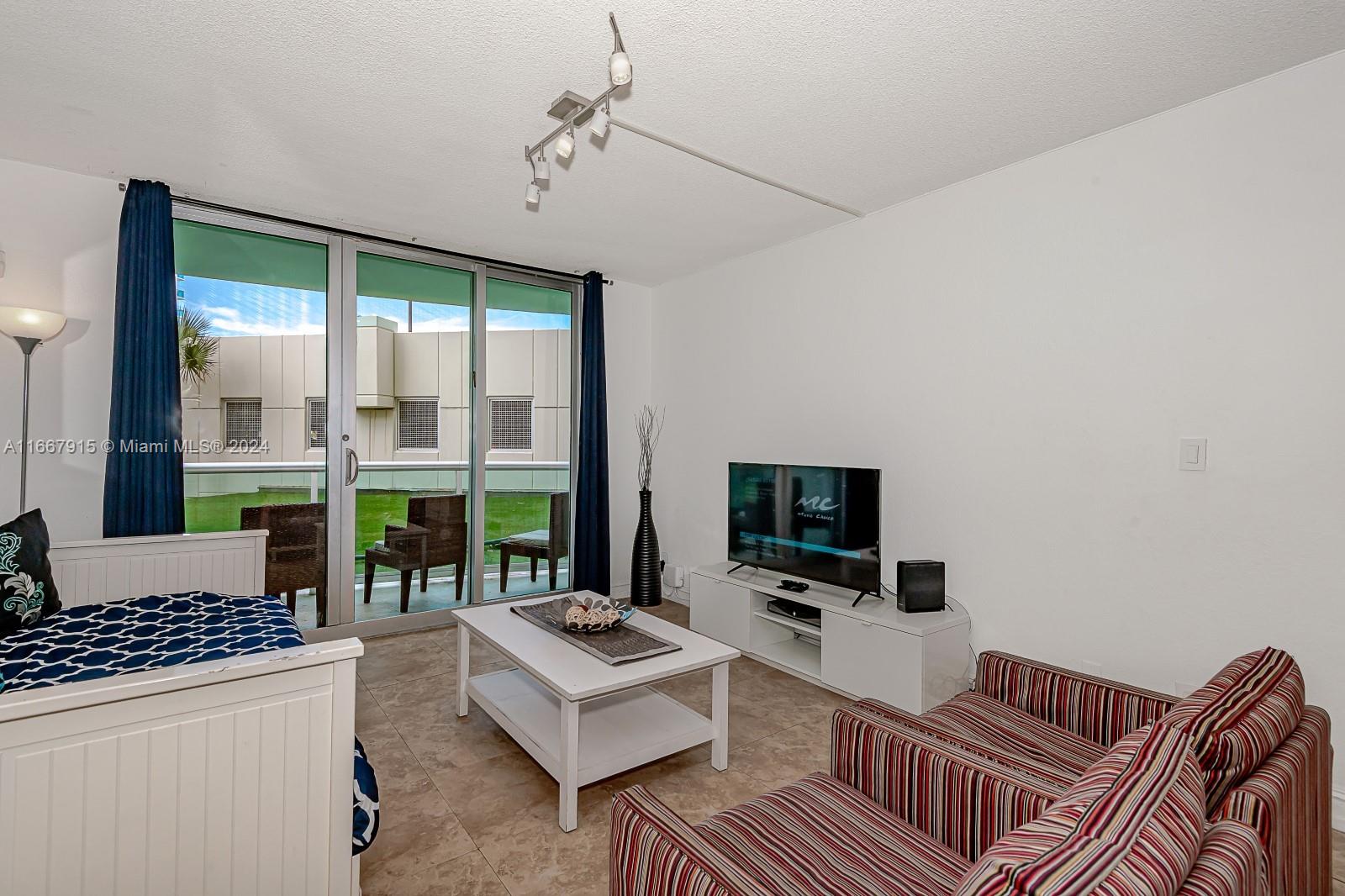 a living room with furniture a flat screen tv and a large window