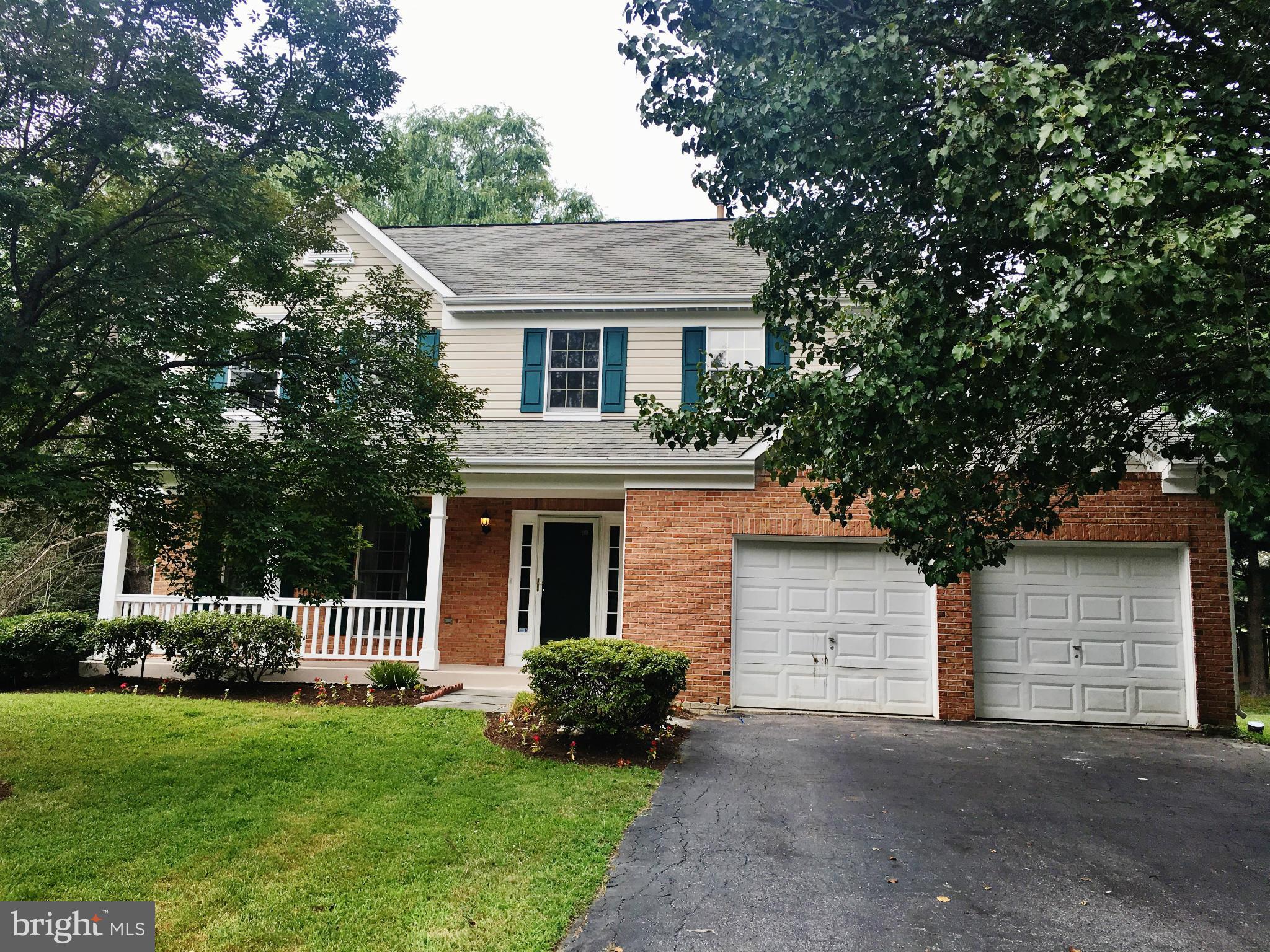 a front view of a house with a garden and trees