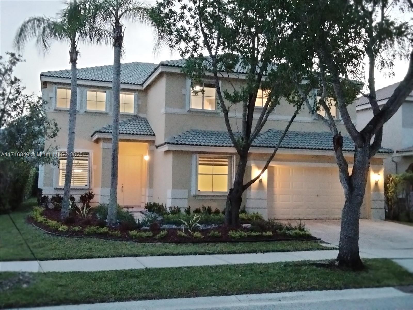 front view of house with a yard and palm trees