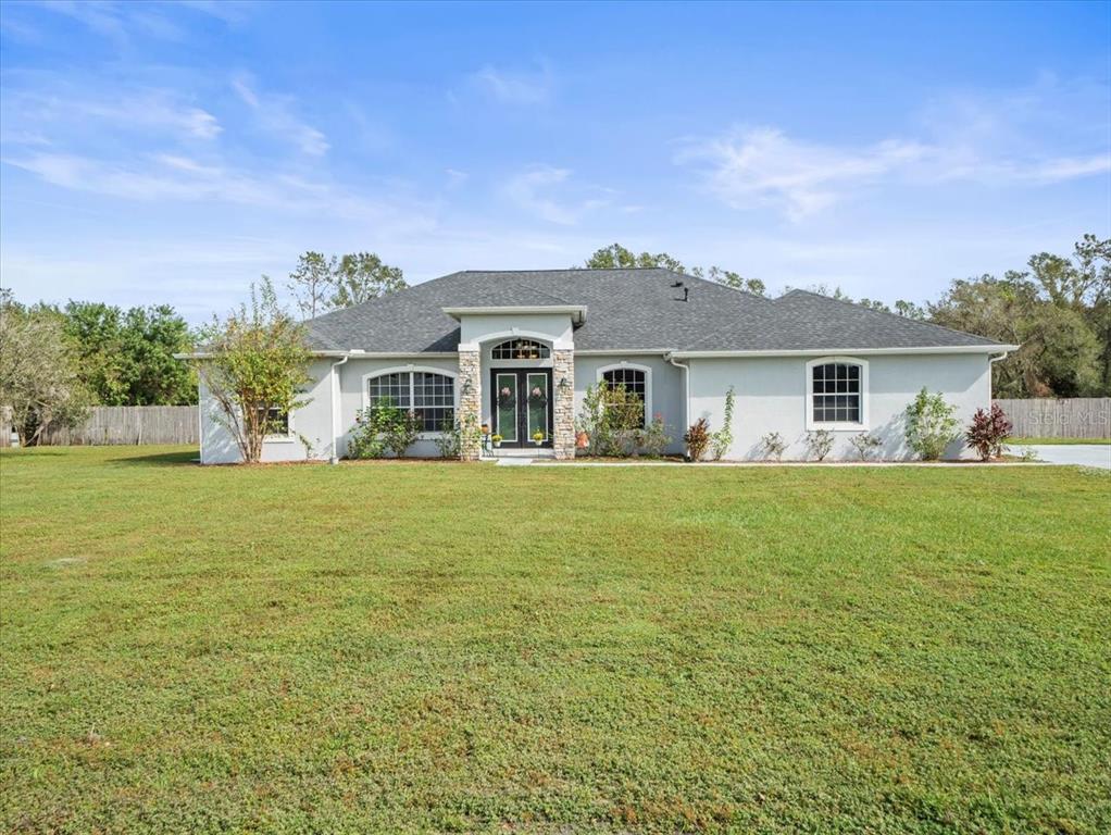 a front view of house with yard and trees in the background