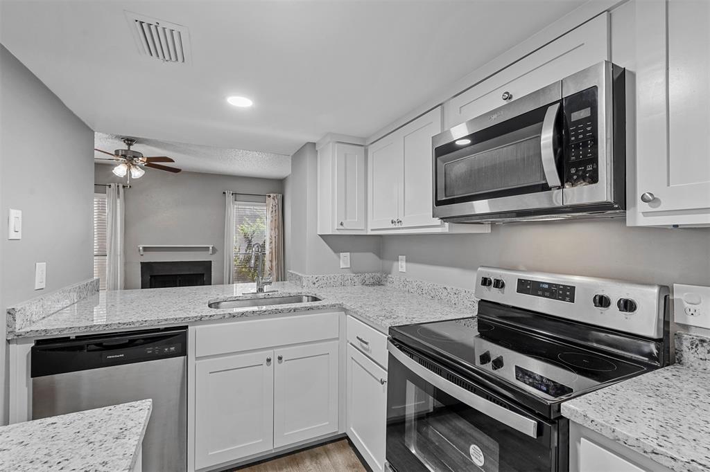 a kitchen with granite countertop a stove microwave and sink