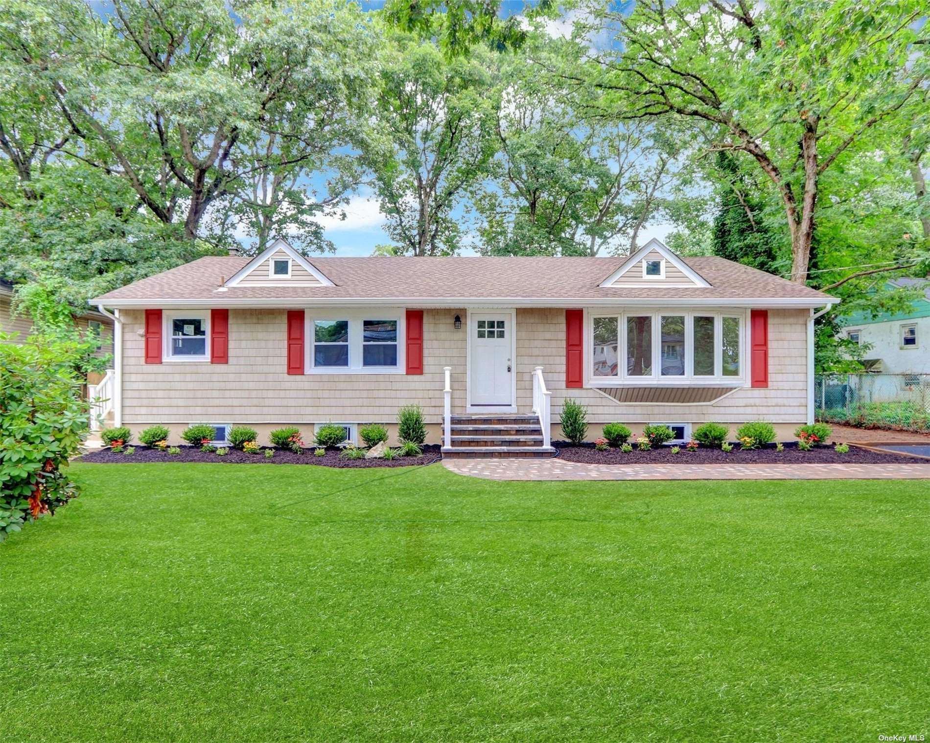 a front view of a house with a garden and trees