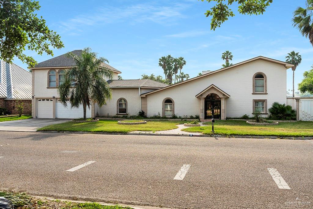 a view of a white house with a yard and palm trees