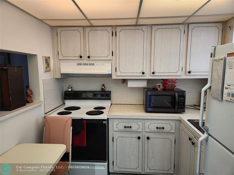 a kitchen with white cabinets and black appliances