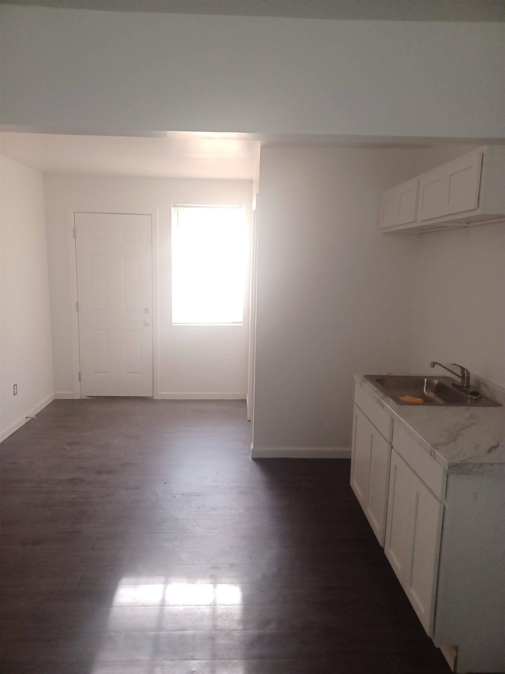 Kitchen with sink, white cabinets, and dark wood-type flooring