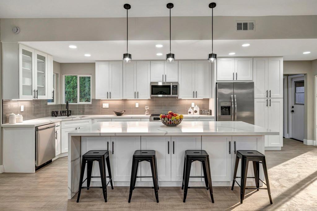 a kitchen with stainless steel appliances granite countertop a table chairs refrigerator and sink