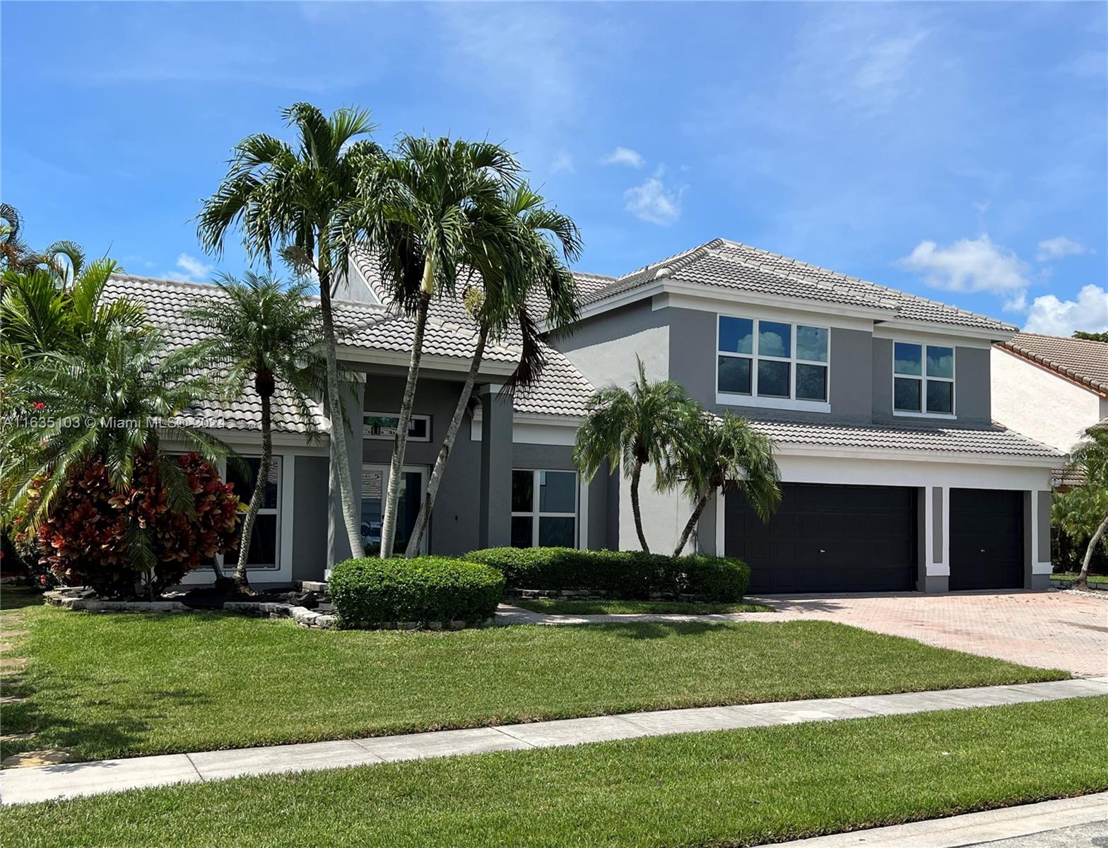 a front view of a house with a yard and palm trees