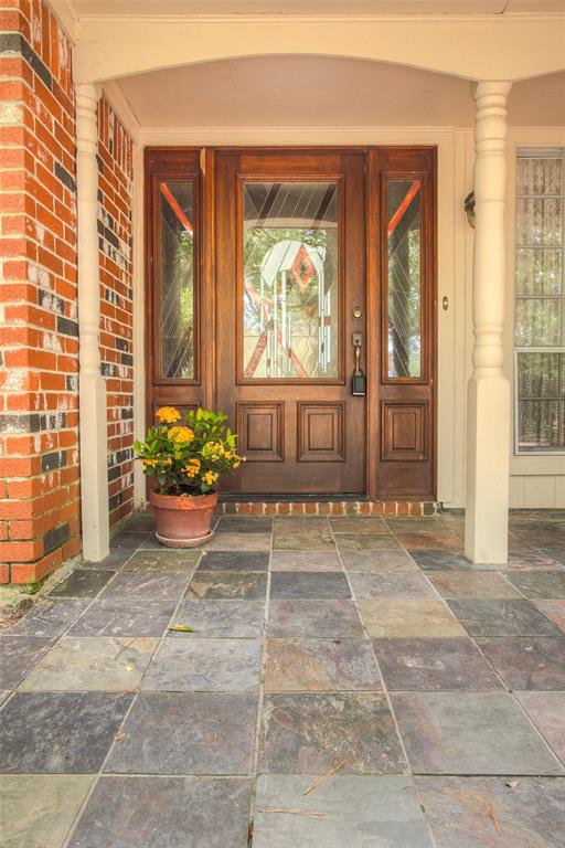 This cozy entryway features a beautiful, custom stained glass front door that allows natural light to filter through, creating a welcoming ambiance. The space is complemented by warm wood trim and set on a slate floor.