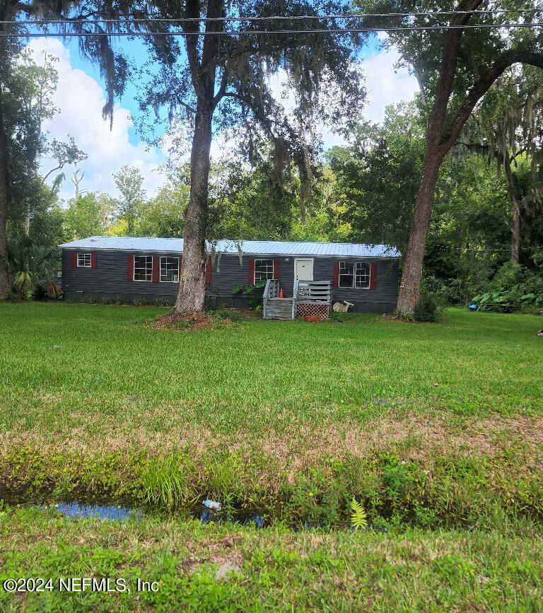 a view of a house with a yard deck and a tree