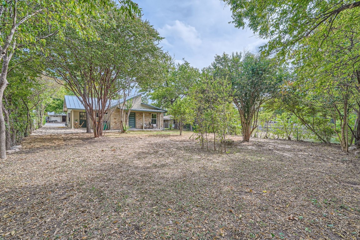 a backyard of a house with large trees and outdoor seating