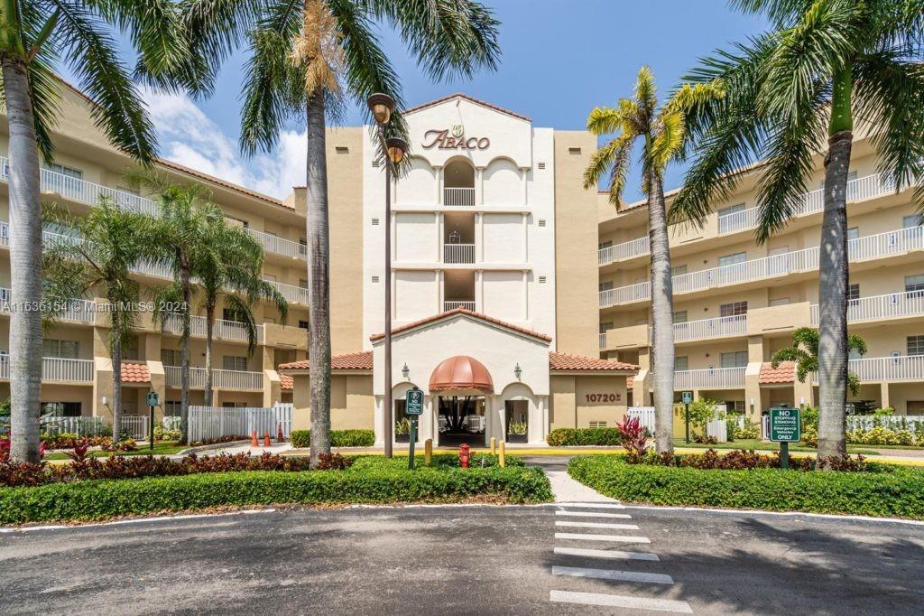 front view of a building with a yard and palm trees