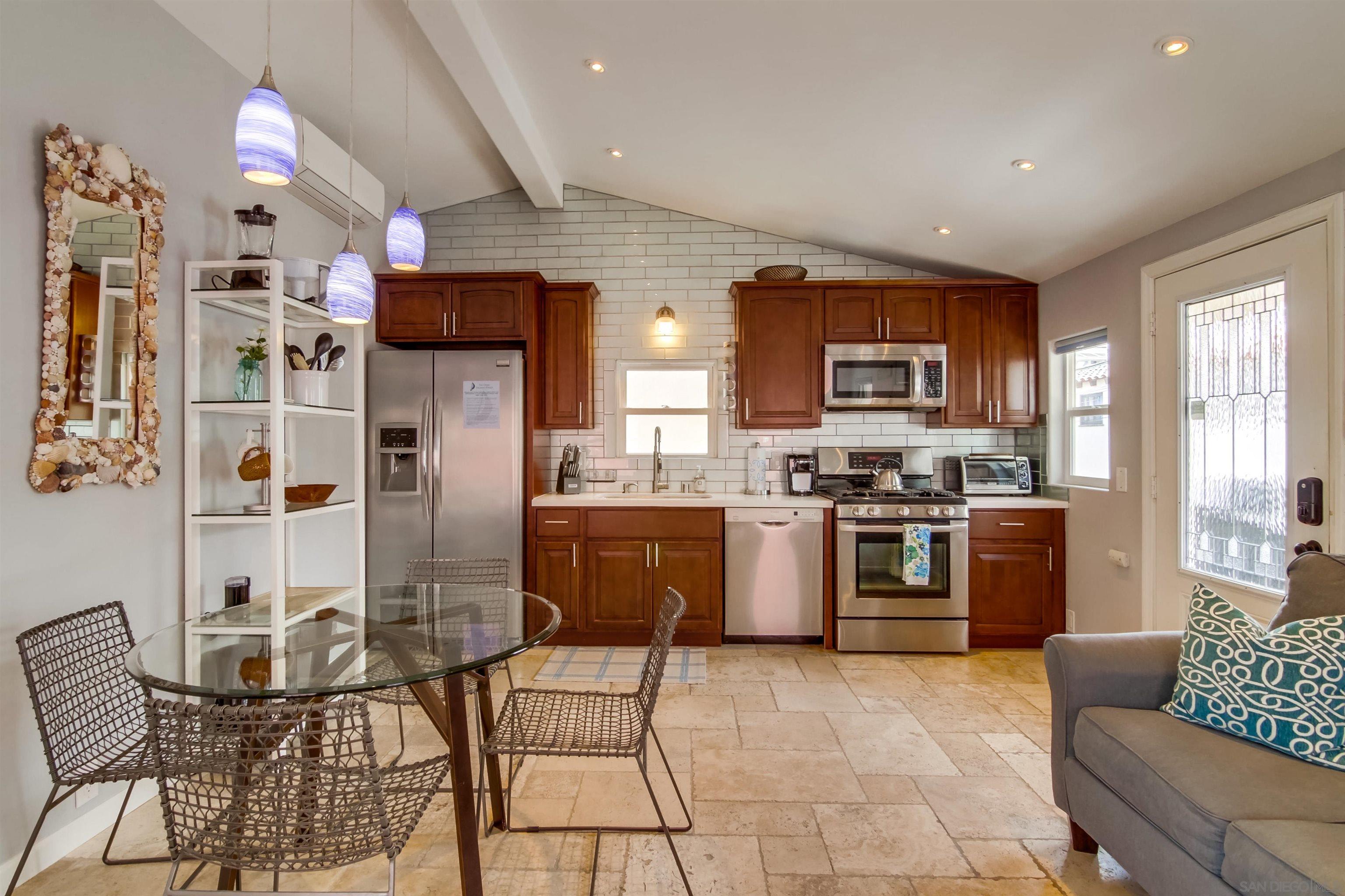 a kitchen with stainless steel appliances kitchen island granite countertop a stove a refrigerator a oven a sink a dining table and chairs with wooden floor