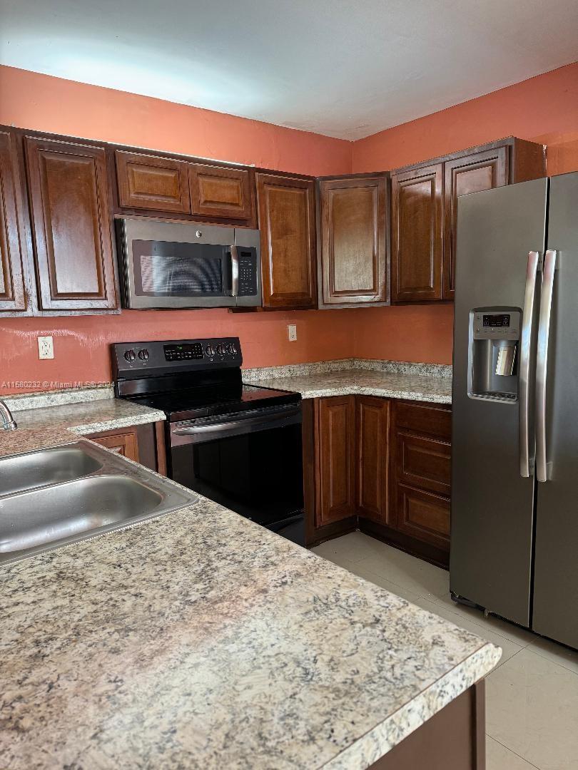 a kitchen with stainless steel appliances granite countertop a refrigerator and a stove top oven