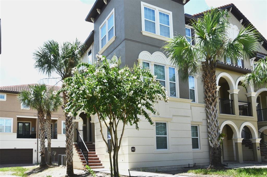 a front view of a multi story residential apartment building with yard and parking