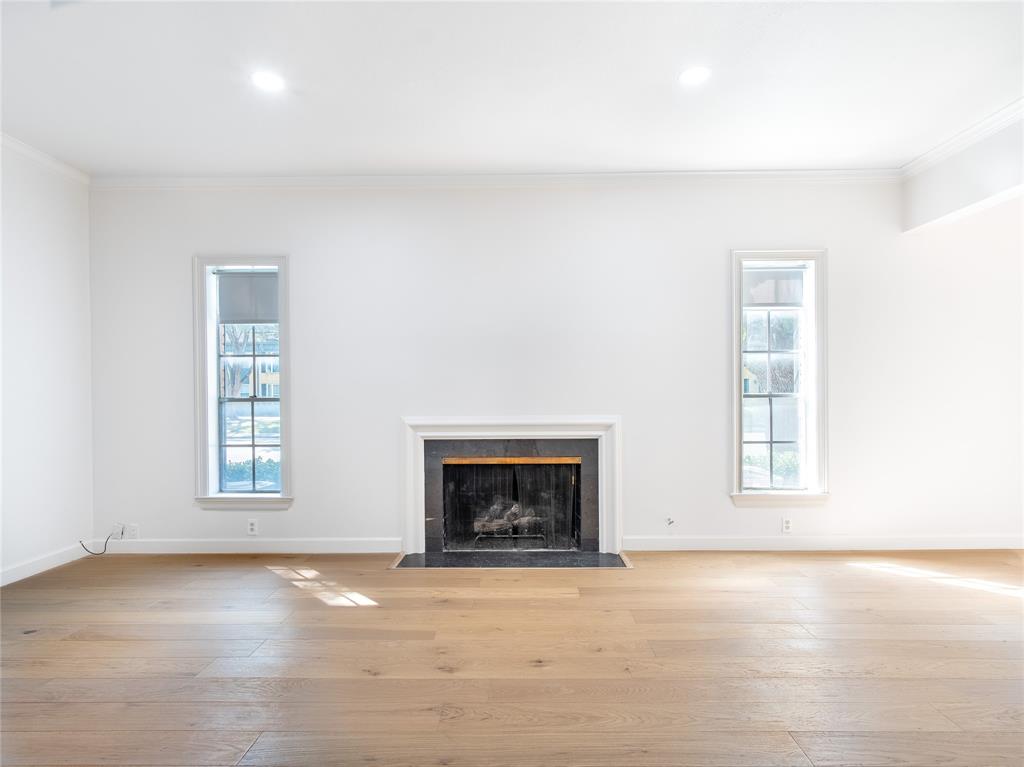 an empty room with windows and fireplace