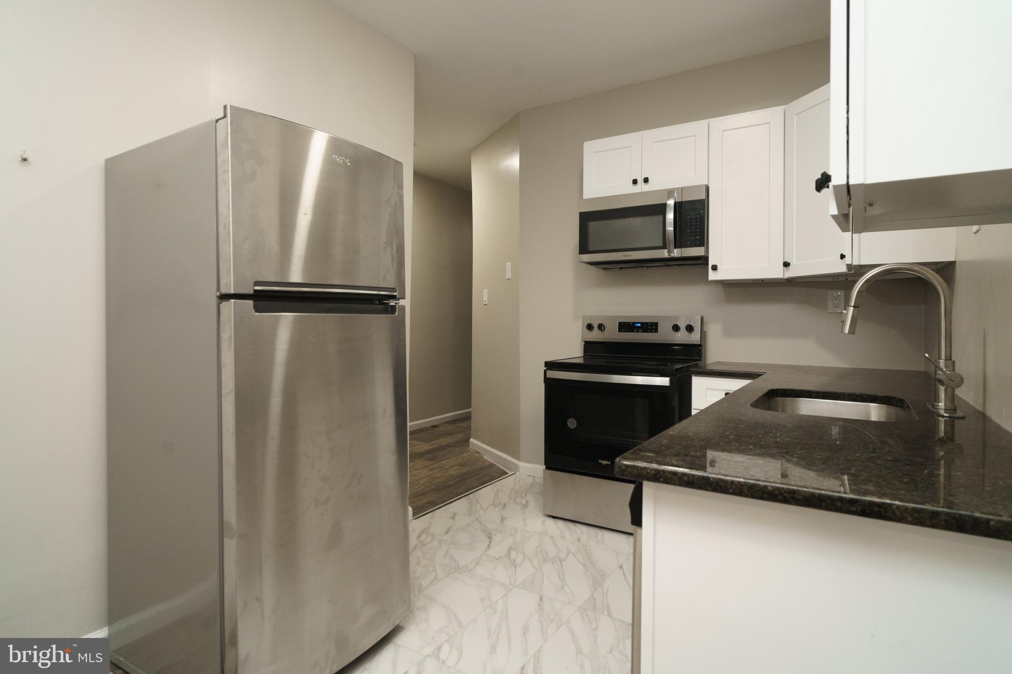 a kitchen with stainless steel appliances granite countertop a refrigerator a stove top oven a sink and dishwasher