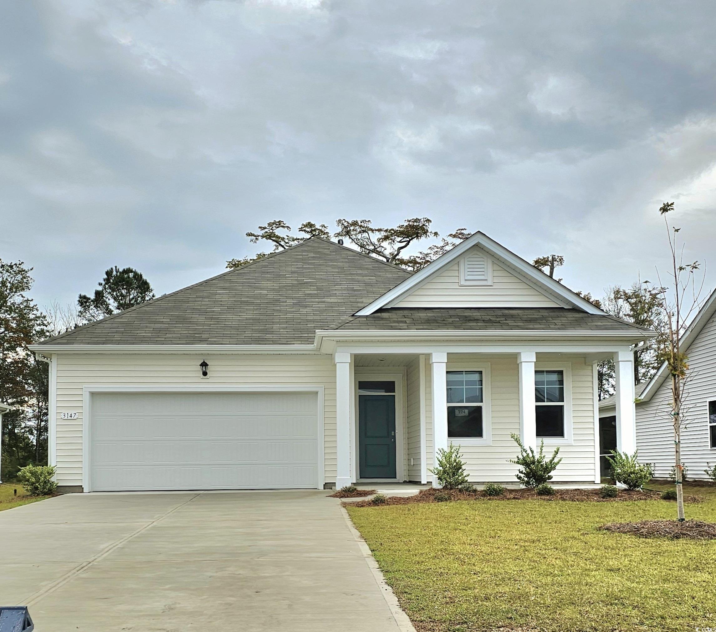 View of front of home with a front yard and a gara