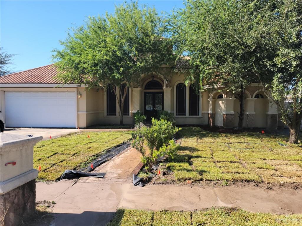 View of exterior entry featuring french doors, a lawn, and a garage