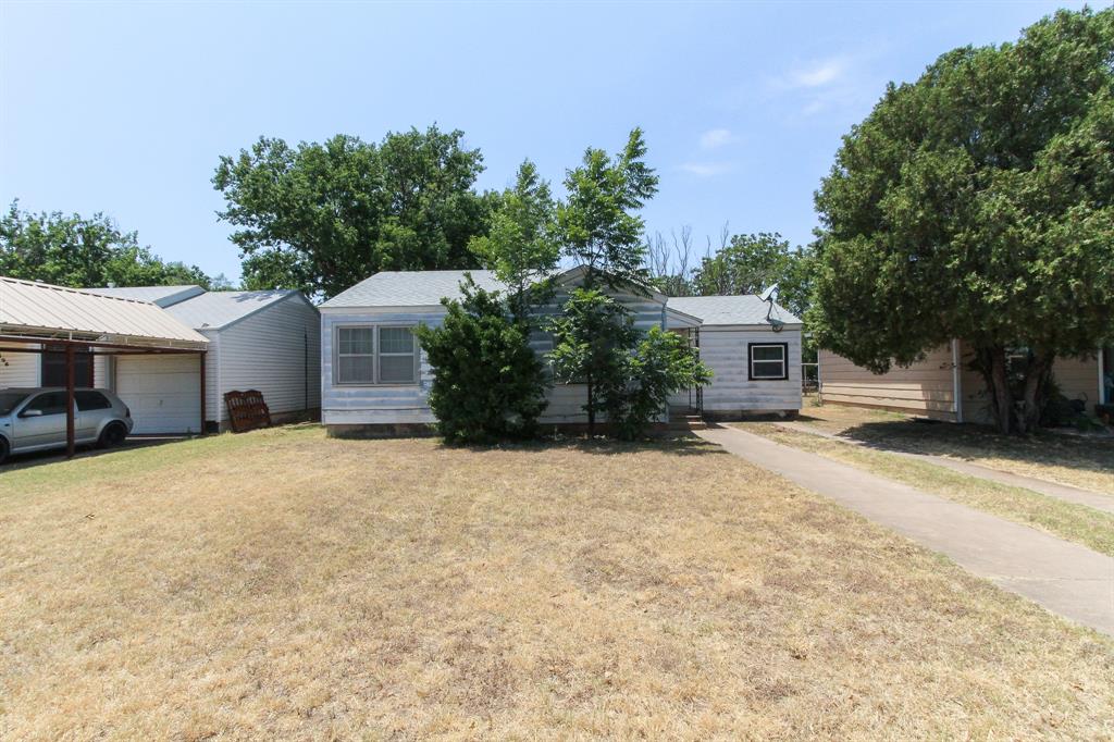 a front view of house with yard and trees in the background