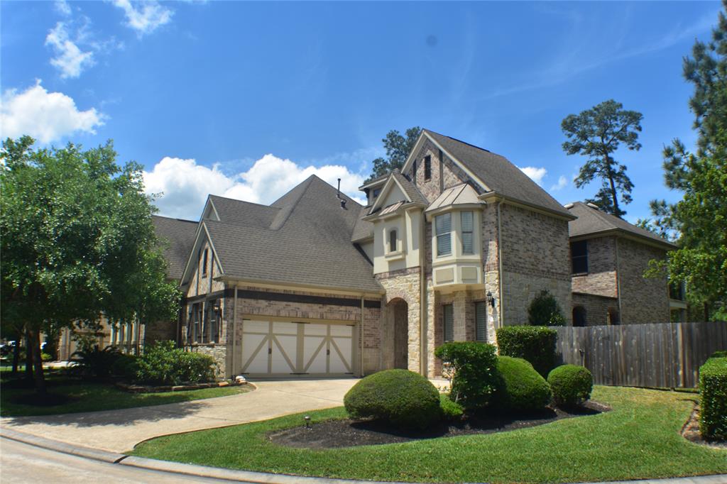 a view of a house with a small yard plants and a large tree