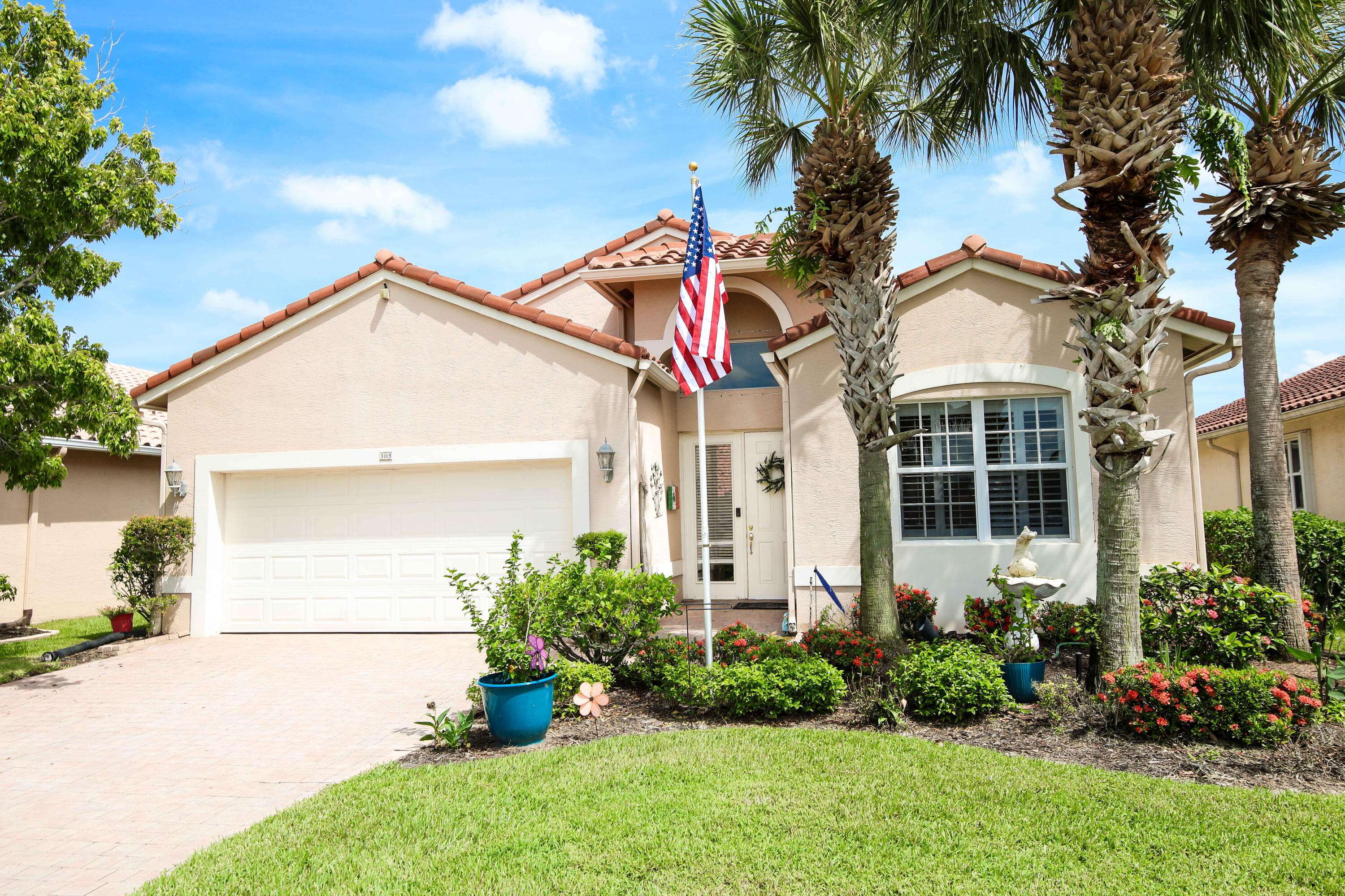 a front view of a house with a yard and potted plants