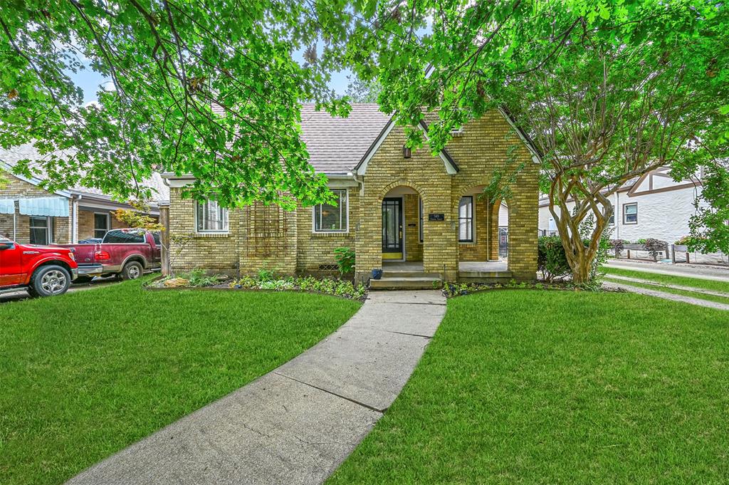 a front view of a house with a garden and trees