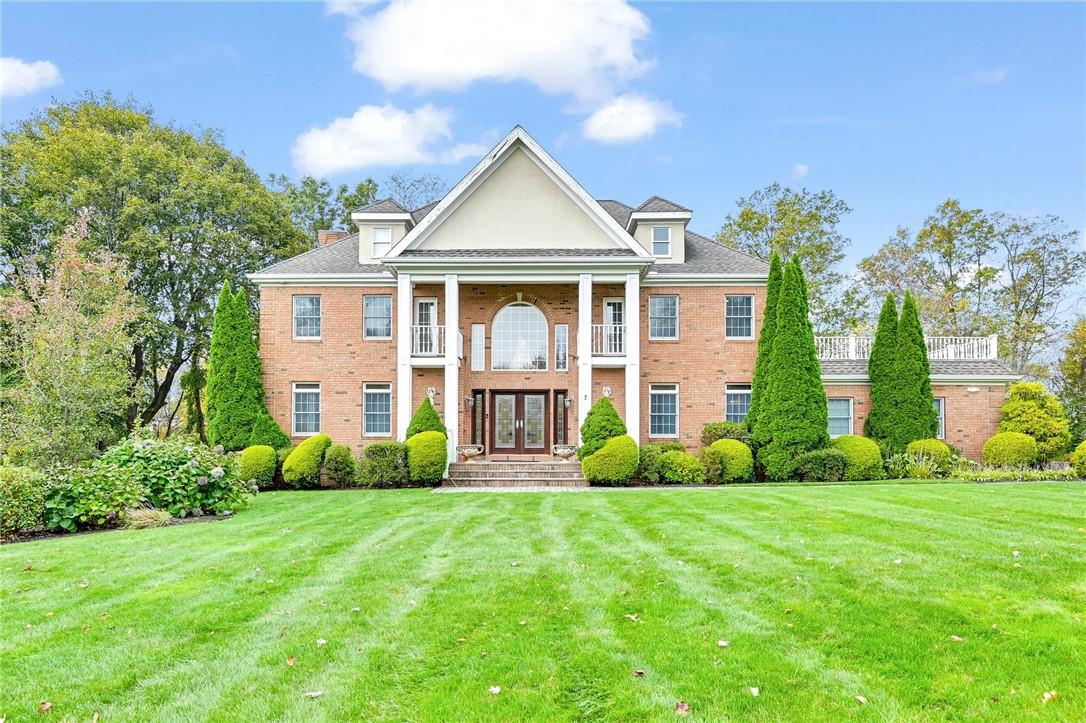 Greek revival house with a balcony and a front lawn