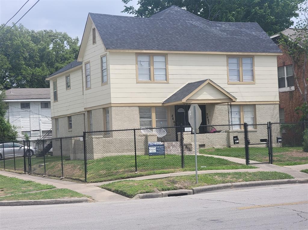 a view of a yard in front of a house with wooden fence