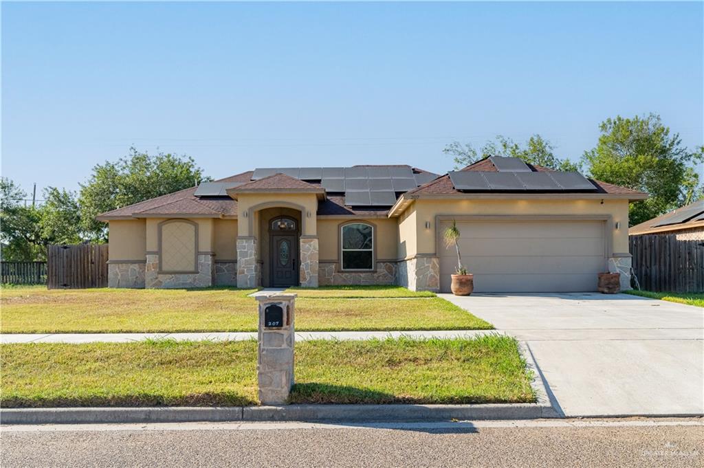 View of front facade with a garage, a front yard, and solar panels