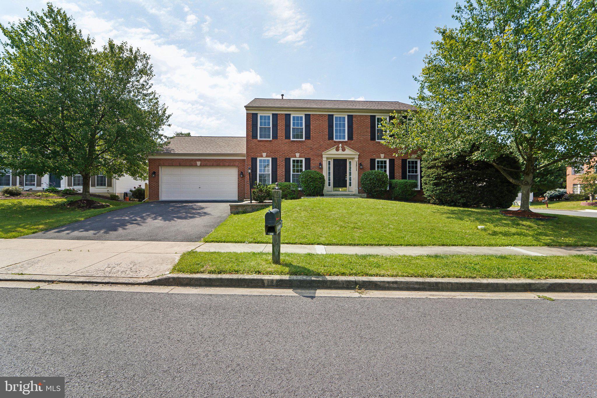 a view of a house with a big yard and large trees