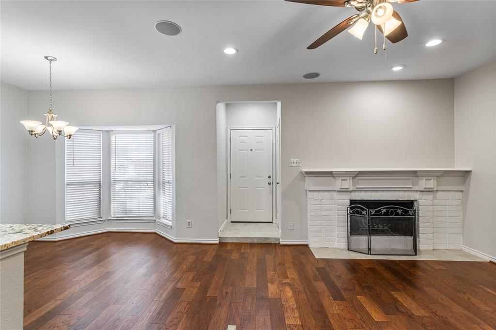 an empty room with wooden floor fireplace and windows