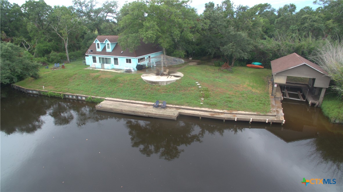 an aerial view of a house with swimming pool a yard and lake view