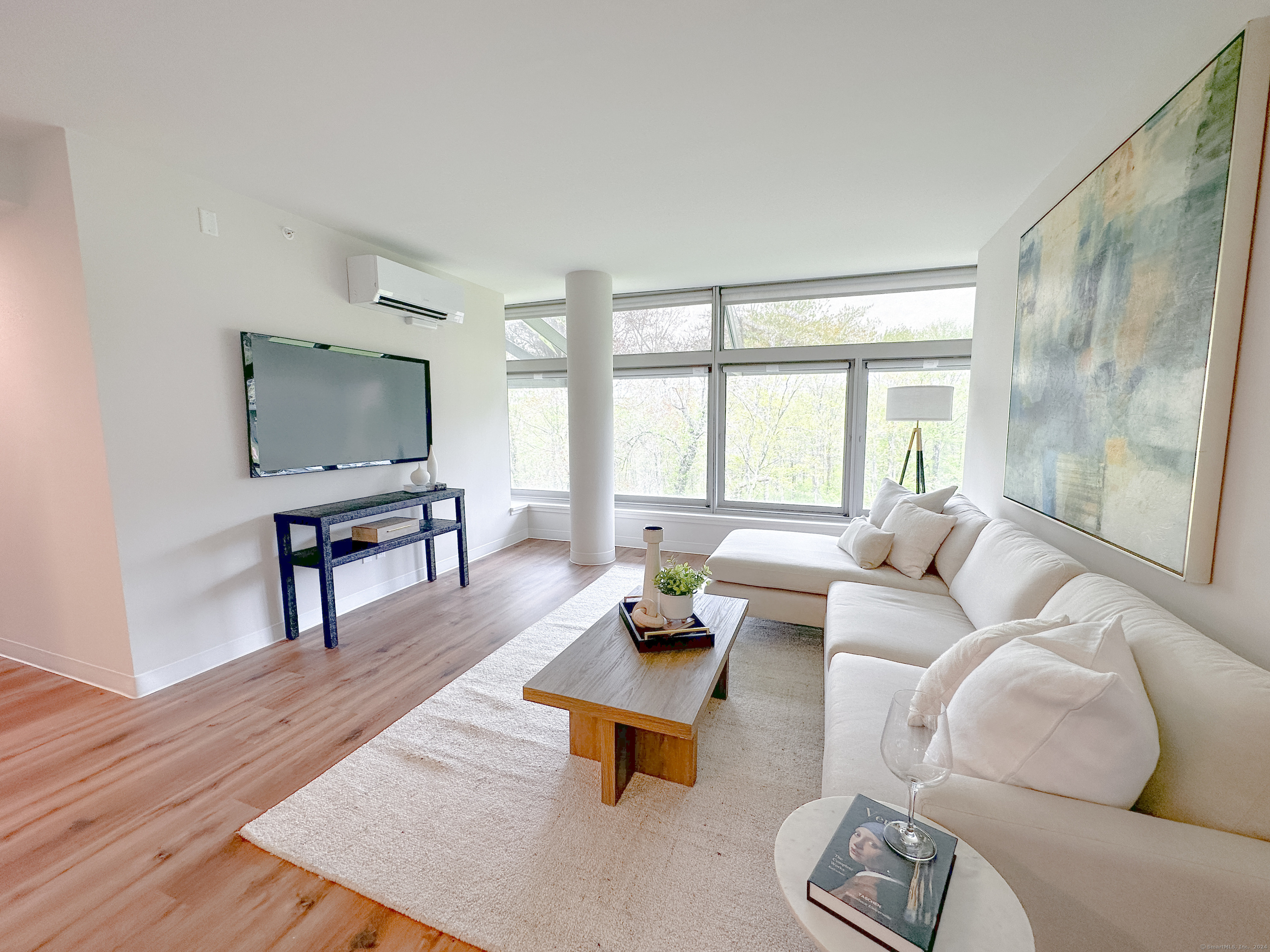 a living room with furniture wooden floor and a floor to ceiling window