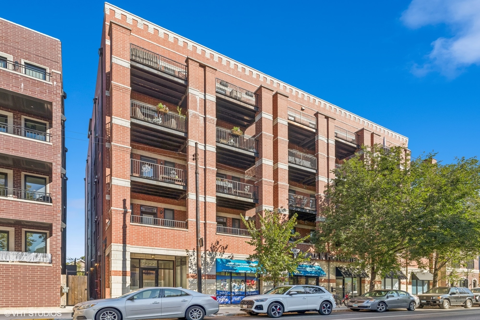 a front view of a building with lot of cars and trees