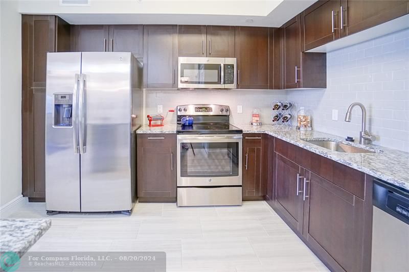 a kitchen with stainless steel appliances granite countertop a refrigerator stove and sink