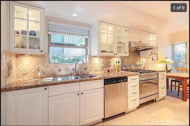 a kitchen with stainless steel appliances granite countertop white cabinets and a large window