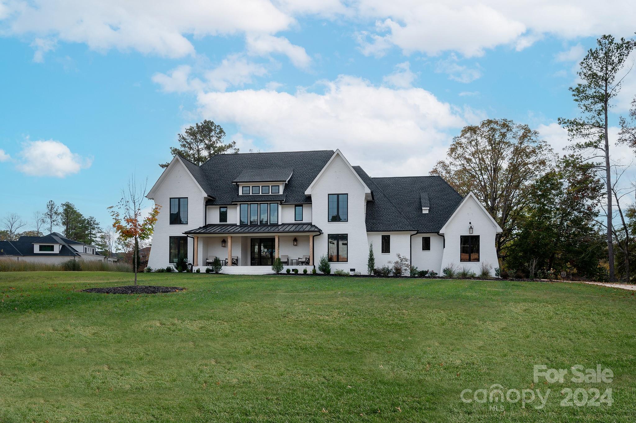 a view of a house with a big yard and large trees