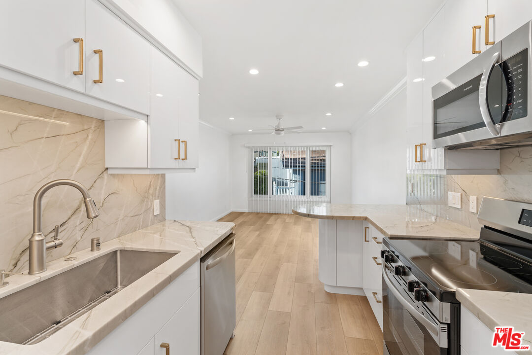 a view of a kitchen with a sink and dishwasher a stove top oven with wooden floor