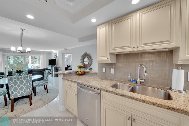 a kitchen with granite countertop a sink white cabinets and chairs