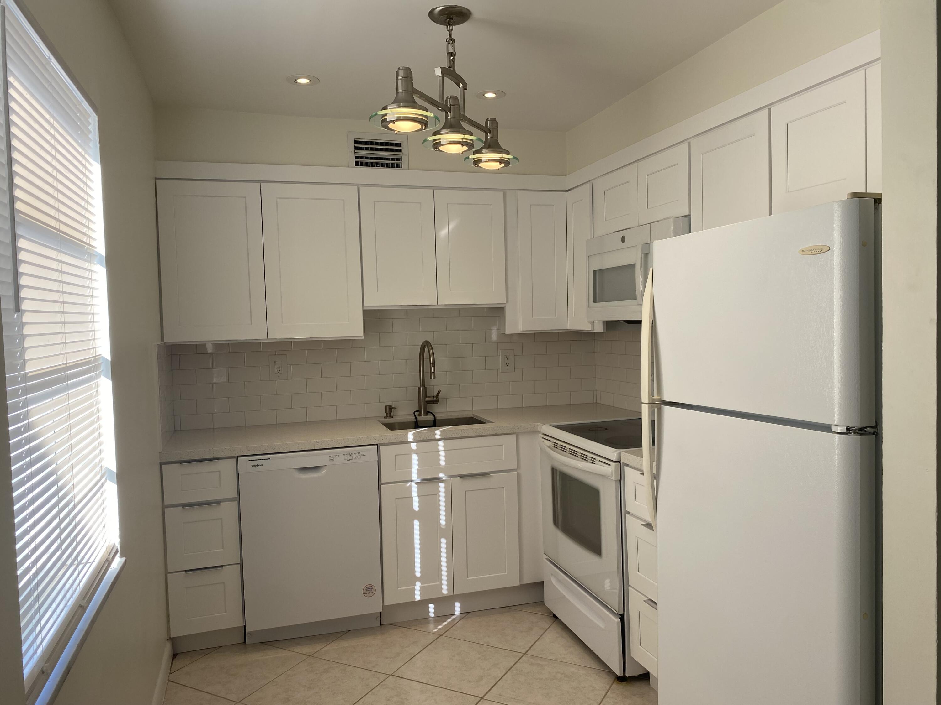 a white refrigerator freezer sitting inside of a kitchen with stainless steel appliances granite countertop white cabinets and a refrigerator