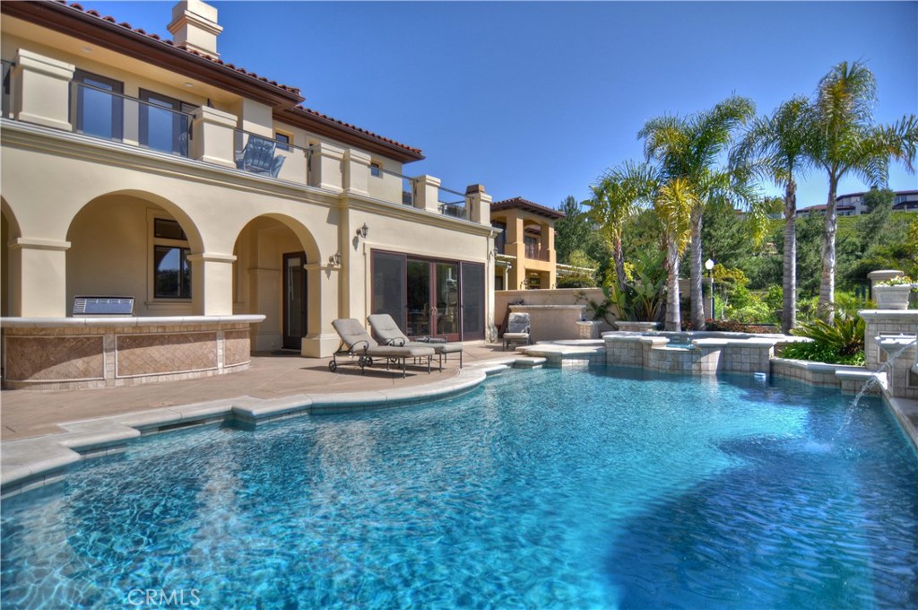 a view of swimming pool with lawn chairs and palm trees